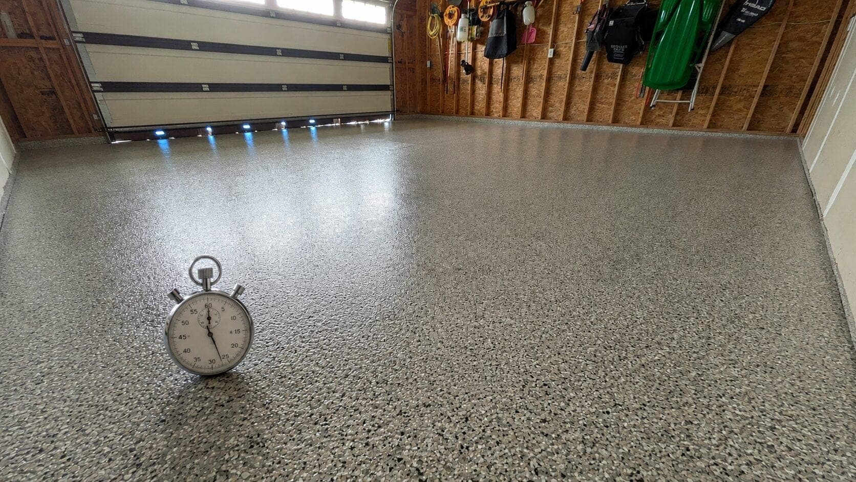 Stopwatch on a professionally coated garage floor showing why quality garage floor coatings take time